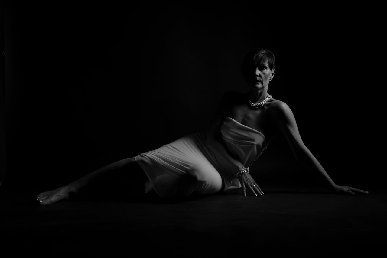 services-01 Dramatic grayscale image of a woman posing elegantly in a studio setting.